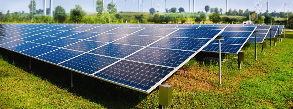 solar-panel-with-wind-turbines-against-mountains.jpg - Flux Solar Energy Solar Panels on the ground showing advancements in technology